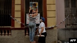 La presidenta de un CDR en La Habana cuelga un retrato de Raúl Castro el 1ro de mayo de 2020. Foto Archivo.