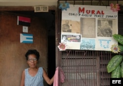 Una mujer posa junto al mural de un Comité de Defensa de la Revolución (CDR)