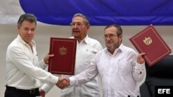 El delegado de las FARC en Cuba, Rodrigo Londoño Echeverri, alias "Timochenko" (d) y el presidente de Colombia, Juan Manuel Santos (i) junto a el presidente de Cuba, Raúl Castro (c) sostienen en sus manos el acuerdo de paz.