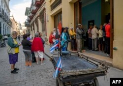 Consumidores hacen cola para comprar alimentos en una bodega en La Habana.