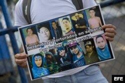 Un joven sostiene un cartel con fotografías de manifestantes detenidos.