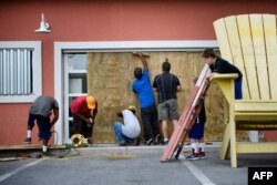 Los trabajadores protegen las ventanas de Marco's Pizza, en Panama City Beach, Florida.