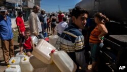 La gente hace fila en un camión cisterna que distribuye agua potable en medio de las secuelas del huracán Ian en La Coloma, provincia de Pinar del Río, Cuba, el 5 de octubre de 2022. (AP Foto/Ramón Espinosa)