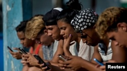 Jóvenes cubanos se conectan a internet desde su teléfono móvil en La Habana. Una de las quejas de los ciudadanos después de la llegada de internet móvil a la isla es que la conectividad es demasiado cara, lenta y censurada por el régimen. (YAMIL LAGE / AFP)