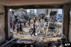 La gente se reúne junto a los escombros de un edificio después de un ataque aéreo israelí en Rafah, en el sur de la Franja de Gaza, el 13 de octubre de 2023.