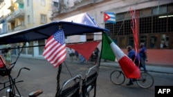 Un bicitaxi con banderas de Cuba y EEUU en una calle de La Habana. (Yamil Lage/AFP).