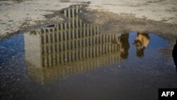 La embajada de EEUU en La Habana reflejada en un charco de agua.