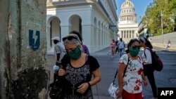 Mujeres usando máscaras caminan por una calle de La Habana