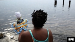 Una mujer reza frente al mar antes de participar, junto a cientos de personas, en la procesión de la Virgen de Regla, en Cuba.