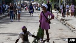 Una pareja de peregrinos cubanos participa en la procesión de San Lázaro mientras una mujer sostiene una rama de palma en la iglesia El Rincón en La Habana el 16 de diciembre de 2024