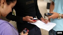 Tres jóvenes usan sus teléfonos móviles en La Habana (Cuba).