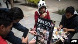 Una pareja de migrantes venezolanos pinta billetes en las calles de Bogotá para protestar contra la situación económica de su país. (Archivo)