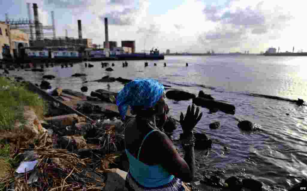 Una mujer reza frente al mar antes de participar, junto a cientos de personas en la procesión de la Virgen de Regla, en Cuba.