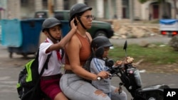 Foto de archivo. Una mujer transporta niños en una moto eléctrica por las calles de La Habana Vieja, Cuba. (Foto AP/Ismael Francisco)