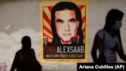 Peatones caminan cerca de un cartel que pide la libertad del empresario colombiano y enviado especial venezolano Alex Saab, en Caracas, Venezuela. 