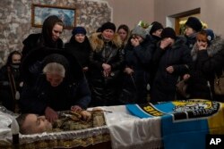 Familiares y amigos velan el cadáver del sargento de policía Roman Rushchyshyn, en la aldea de Soposhyn, a las afueras de Leópolis. (AP Foto/Bernat Armangué)