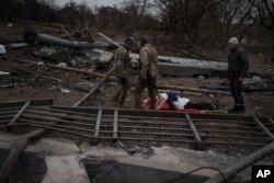 El cuerpo de un civil, que murió por causas desconocidas, se ve en una camilla en un camino empleado como ruta de evacuación para salir de Irpín, a las afueras de Kiev. (AP Foto/Felipe Dana)