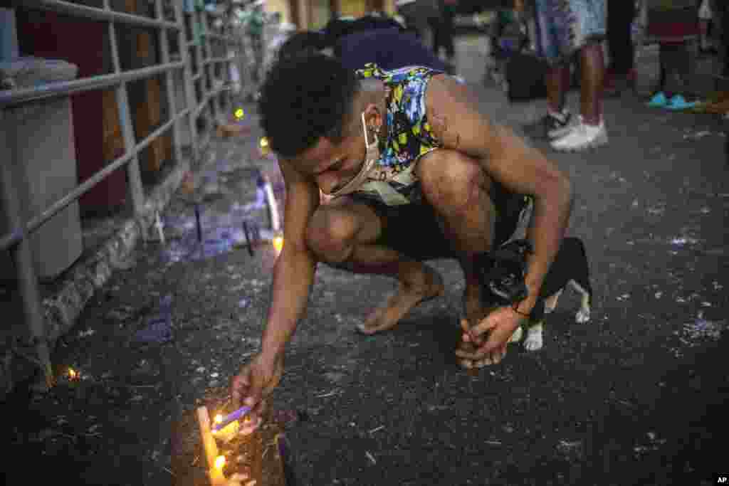 Un seguidor de San Lázaro, acompañado de su perro, enciende una vela al santo durante la peregrinación al santuario de El Rincón, en La Habana.