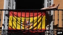 Una mujer toma el sol en su balcón en Madrid detrás de una bandera española. (Gabriel BOUYS / AFP)