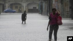 Residentes caminan por una calle inundada por la lluvia provocada por el huracán Idalia en La Habana, Cuba, la madrugada del martes 29 de agosto de 2023. (AP/Ramon Espinosa)