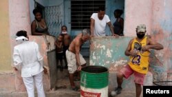 Una enfermera pide a una familia acudir al centro de vacunación en un barrio de La Habana. (REUTERS/Alexandre Meneghini).