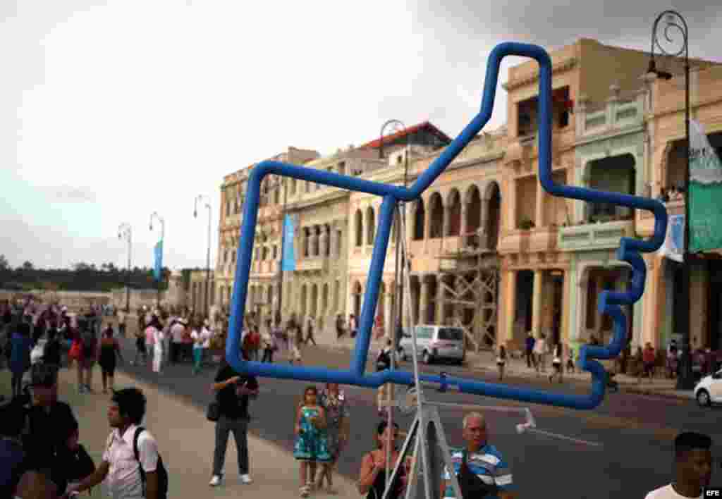 Personas caminan junto a la obra "Suite Emotion" de Alexander Guerra, expuesta en el Malecón hoy, domingo 24 de mayo, donde ha sido inaugurada la exposición "Detrás del Muro" como parte de la XII Bienal de Arte de La Habana.