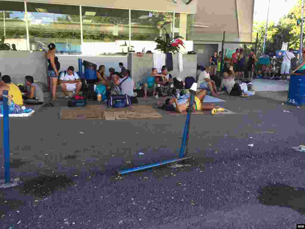 Grupos de cubanos descansan bajo la mirada de las autoridades de Migración.