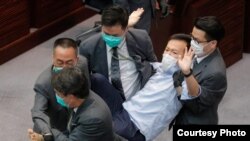 Los guardias de seguridad arrastran al legislador pro democracia Ray Chan durante una reunión legislativa el 8 de mayo en Hong Kong. 