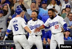 El receptor de los Dodgers de Los Ángeles Will Smith (16) celebra con el jardinero Mookie Betts (50) y el jardinero Teoscar Hernández (37) tras batear un jonrón de dos carreras en la tercera entrada contra los Mets de Nueva York, 20/10/2024. (Jayne Kamin-Oncea-Imagn Images )