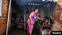 Una cubana cocina con carbón en su casa inundada a causa del huracán Milton. Lsa acumulaciones de agua y basura favorecen la proliferación del Dengue y el Oropouche. 