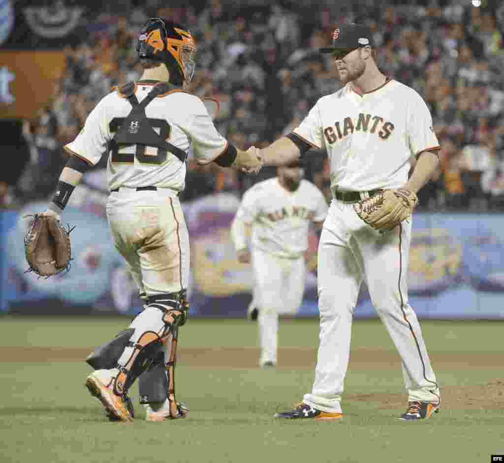 El lanzador Hunter Strickland (d) y el receptor Buster Posey (i) celebran la victoria sobre los Reales. 