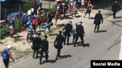 Foto Archivo. Boinas negras caminan junto a personas que permanecen en una cola.